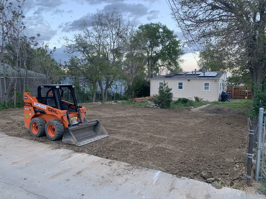 Skid-steer finish work on a tight residential lot with clean edges at the walk.